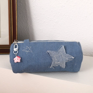Detail of blue denim pencil case featuring stitched stars and a pink star charm