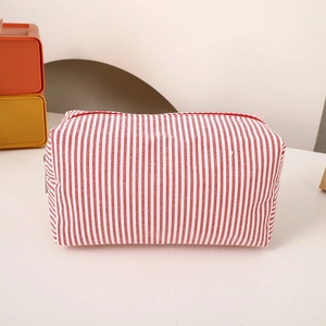 Close-up of red and white striped cotton pencil case with metal zipper on a desk