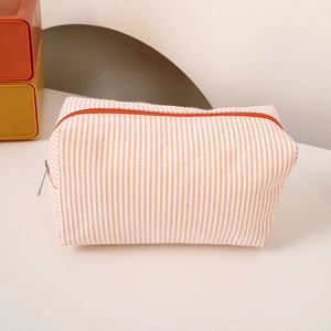 Detail of orange and white striped canvas pencil case with a metal zipper closure