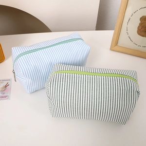 Detail of striped canvas stationery bags with metal zippers in blue and green
