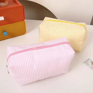 Detail of pink and yellow striped canvas pencil cases with top zipper on a desk