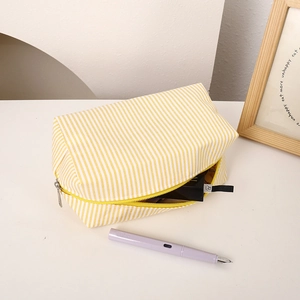 Detail of yellow striped fabric pencil case with stationery and cosmetics inside