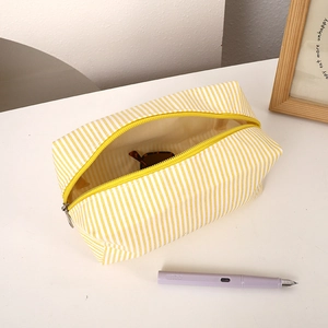 Detail view of a yellow striped canvas pencil case with zipper and large opening