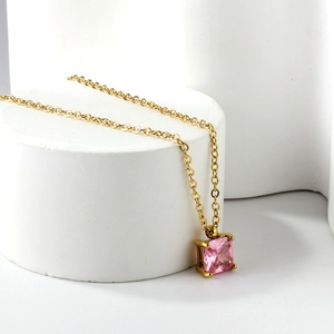 Collier doré élégant avec pendentif en pierre rose carrée sur un présentoir blanc épuré