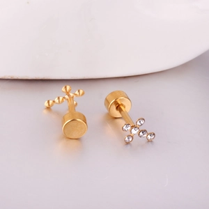 Detailed view of asymmetric gold cross stud earrings with cubic zirconia and metal beads