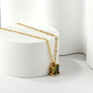Collier en acier doré 18K avec pendentif carré vert olive sur un support blanc moderne