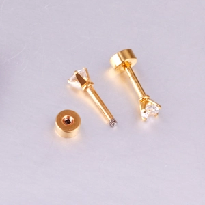 Vue détaillée des boucles d'oreilles dorées à vis avec zircons ronds à quatre griffes