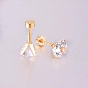 Macro detail of gold four-prong stud earrings with clear round-cut zircon and screw backs