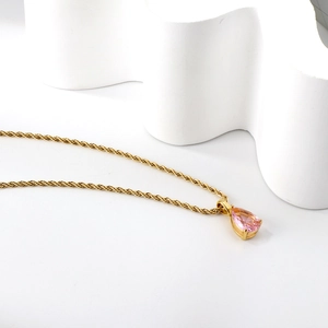 Collier doré avec pendentif cristal rose goutte d'eau sur fond élégant minimaliste