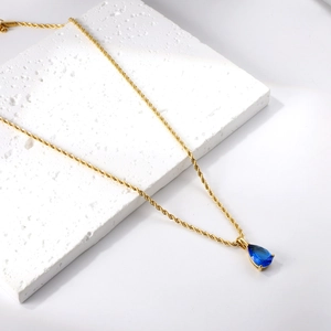 Gros plan du pendentif goutte d'eau bleue sur une chaîne torsadée dorée pour femmes