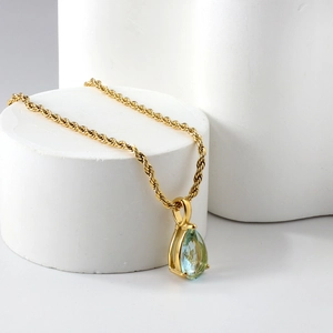 Détail du pendentif goutte en cristal bleu clair sur chaîne torsadée dorée 18 carats