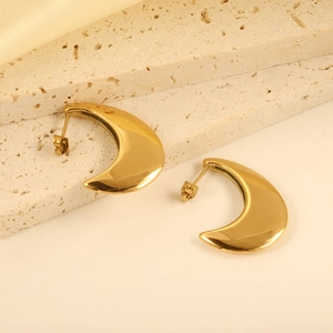 Detailed view of high-polish gold crescent stud earrings on a textured stone display