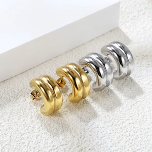Detailed view of chunky C-shape hoop earrings in polished gold and silver steel finish