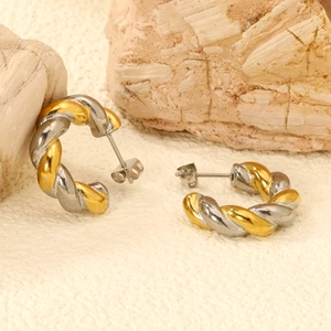 Close-up of twisted stainless steel earrings with butterfly backs on a textured stone