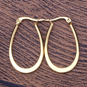 Macro shot of polished gold U-shape oval hoop earrings with shiny metallic finish