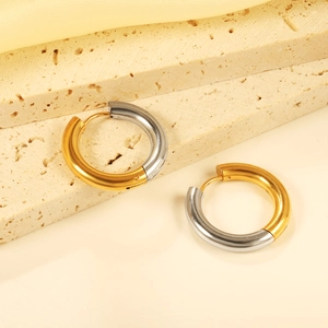 Close-up of chunky irregular gold and silver dual-tone stainless steel hoop earrings
