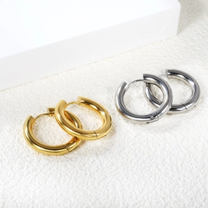 Close-up of polished gold and silver stainless steel thick hoop earrings with hinge closure
