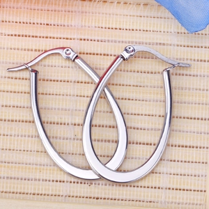 Polished silver stainless steel oval hoop earrings on a light bamboo surface