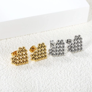 Close-up of gold and silver heart-shaped stud earrings made of tiny polished metal beads