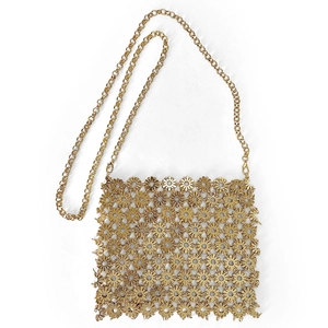 Detail of laser-cut gold metal flower pattern on crossbody bag with chain strap