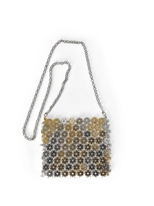 Detail of handcrafted interlocking sunburst metal rings and chain on crossbody bag