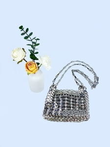 Detailed view of silver metal woven chain bag with handmade round sequin ring texture