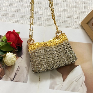 Detail view of handmade gold and silver metal sequin chain bag among roses and magazine
