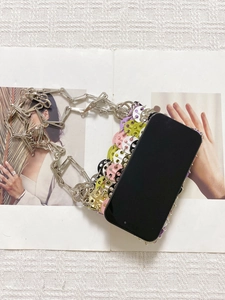 Detail of colorful disc chainmail phone bag with metallic silver shoulder strap on magazine