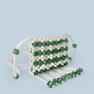 Detailed macro of handmade pearl and green crystal mini crossbody bag with bead tassels