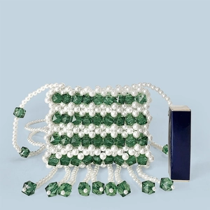 Detail of handmade mini pearl bag with green crystal beads and long fringe tassel
