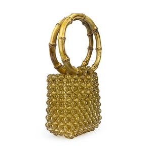 Close-up of handmade amber beaded handbag featuring natural bamboo ring handles