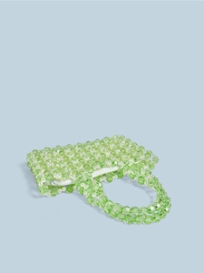 Gros plan des perles de cristal vert et perles blanches sur un sac à main tissé