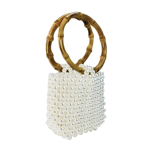 Detail of white pearl beads and brown bamboo-style resin handle on a handmade handbag