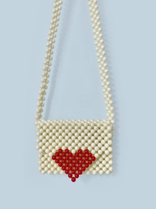 Détail du sac bandoulière fait main en perles blanches avec un motif de cœur rouge