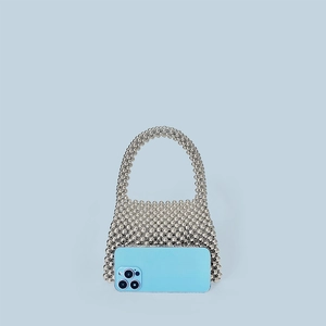 Vue détaillée du mini sac à main en perles argentées avec téléphone pour échelle