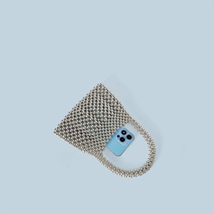 Vue macro d'un mini sac à main perlé argenté avec un téléphone montrant sa contenance