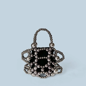 Close-up of silver hollowed-out beaded bucket bag with a black inner drawstring pouch