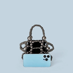 Detailed view of silver beaded bucket bag next to a phone showing compact storage size