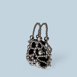 Close-up of a silver beaded handbag with a hollow mesh structure and black inner pouch