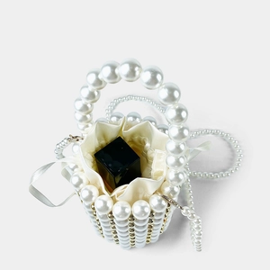 Detail of beaded pearl bucket bag with ivory satin drawstring liner and lipstick