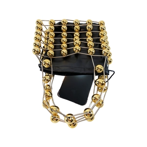 Detailed shot of golden hollow metal frame handbag with black satin drawstring pouch