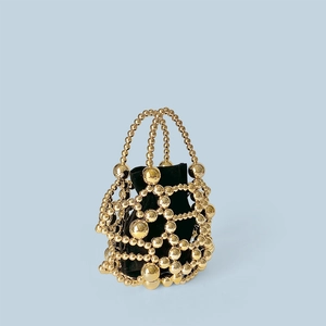 Detail of gold beaded bucket bag featuring a black velvet drawstring pouch and metal mesh