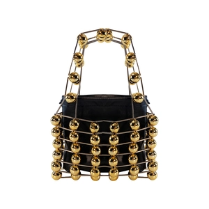 Detailed shot of the gold hollow metal cage and polished spheres on the handbag