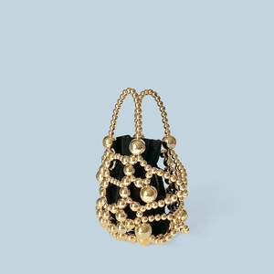 Detail of a gold beaded hollow bucket bag with a black satin drawstring pouch