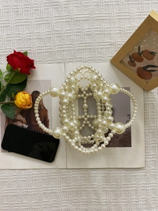 Detail of handmade pearl beaded handbag with elegant geometric weave and ring handle