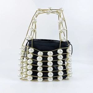 Detail of woven gold metal frame with large white pearls and black drawstring inner bag