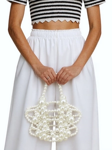 Close-up of handmade white pearl beaded handbag with intricate cutout floral pattern