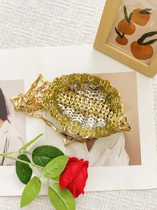 Sac bandoulière artisanal tissé en maille métallique dorée et argentée sur un magazine