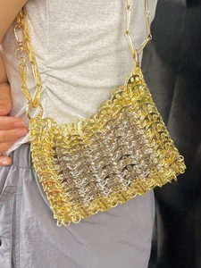 Détail d'un sac bandoulière tissé en métal avec anneaux or et argent et chaîne épaisse