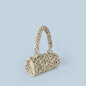 Détail du sac à main cylindrique en perles marbrées avec des anneaux dorés élégants
